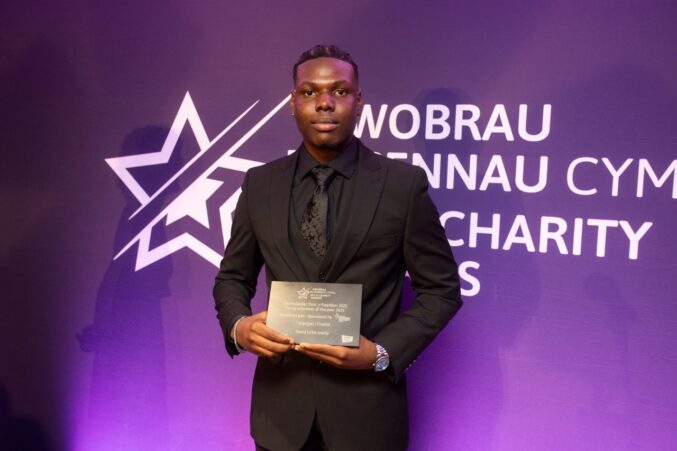 Finalist holding awards plaque on stage.