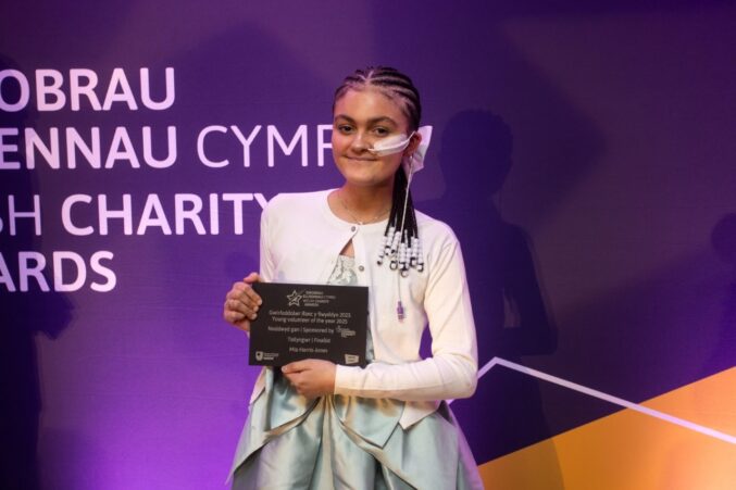 Girl standing on stage holding award and smiling.